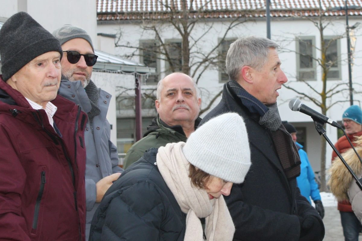 Bürgermeister Christoph Böck verkürzt die zusätzliche Wartezeit mit Infos zur Geschichte der Ismaninger Schäffler. Manchem wäre es angesichts der Temperaturen lieber, sie wären schon da. (Bild: Peter Marwan)