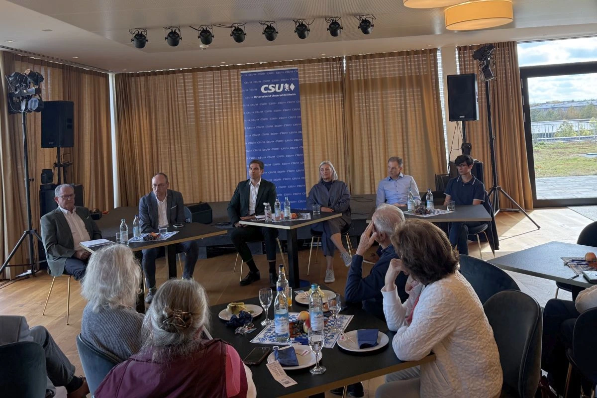 Diskussionsrunde an einem Tisch vor CSU-Aufsteller