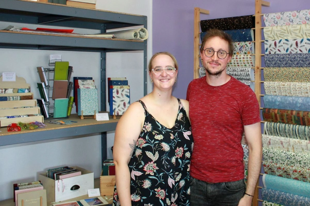Sabrina und Michael Pezala von „Herz & Tinte Papeterie“ im Atelier in der Edisonstraße 11 vor einem Regal mit Papiersorten und fertigen Papeterie-Produkten. (Foto: Peter Marwan)