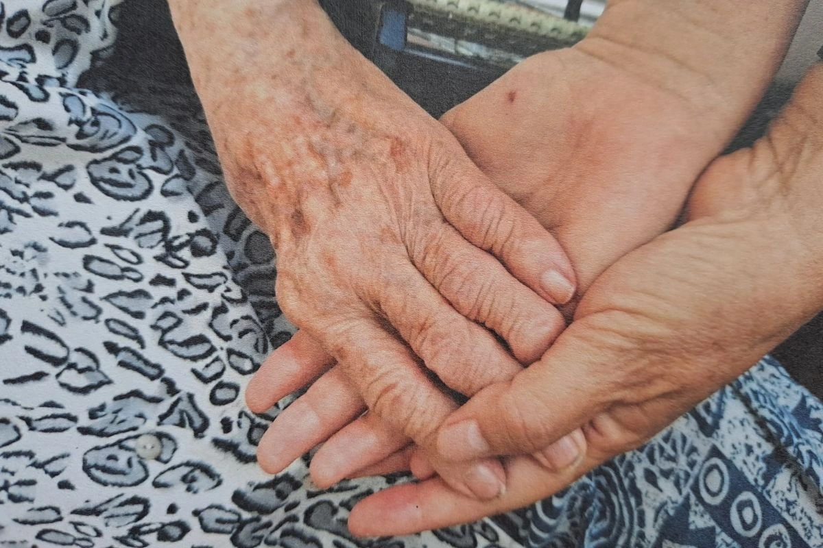 Hand einer alten Frau auf zwei ausgestreckten Handflächen.