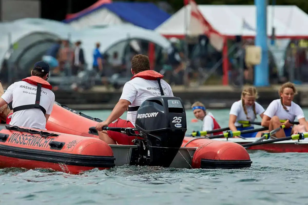 Das Zielrettungsboot Schalu auf dem Weg zu einer anderen Rettung im Zielbereich der Regatta. Eine kollabierte Ruderin (rechts im Bild) wird daraufhin aus dem Boot gezogen, versorgt und zum medizinischen Zentrum transportiert. Foto: Wasserwacht Lohhof