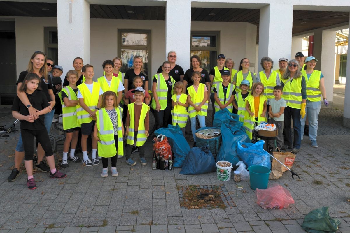 Menschnegruppe in gelben Schutzwesten mit gesammeltem Müll in Säcken im Vordergrund (Bild: CleanUp Unterschleißheim)